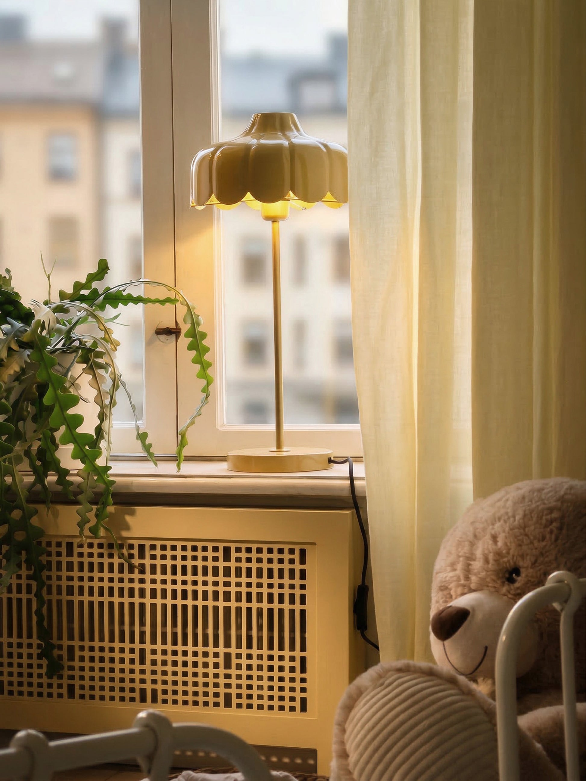 En gul bordslampa i metall i står i ett fönster