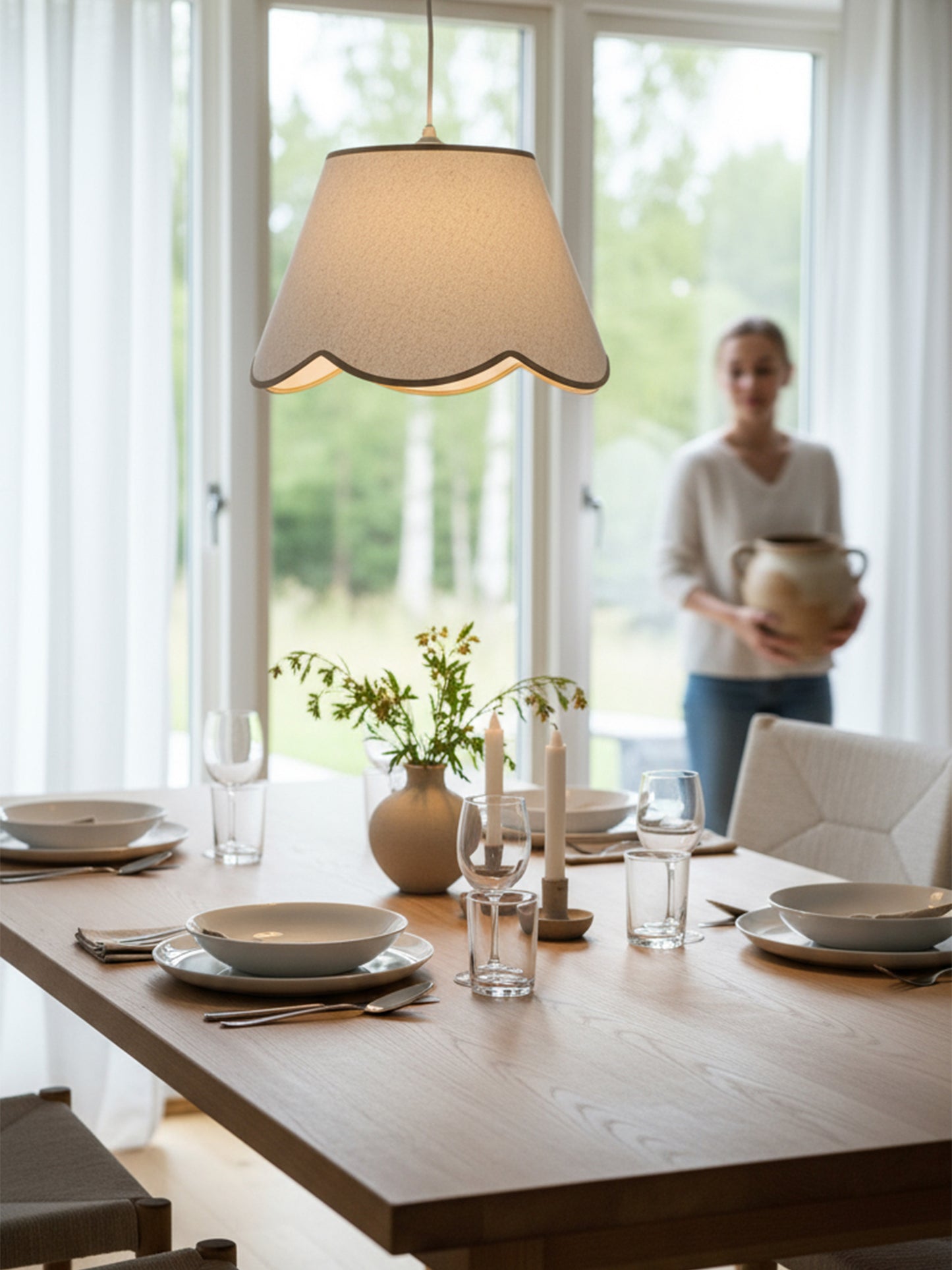 Ett dukat bord med en pendellampa ovanför med beige vågig kant.