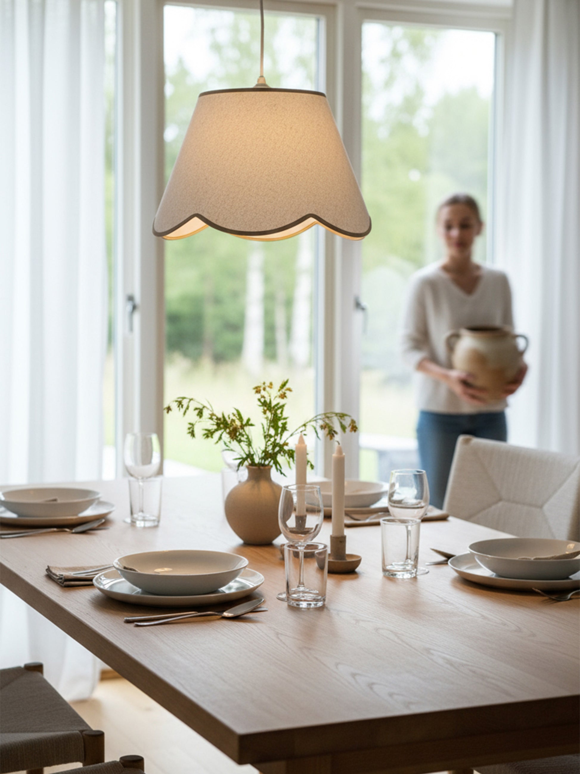 Ett dukat bord med en pendellampa ovanför med beige vågig kant.