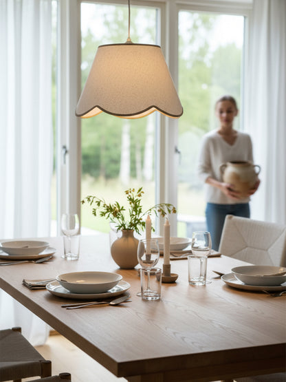 Ett dukat bord med en pendellampa ovanför med beige vågig kant.